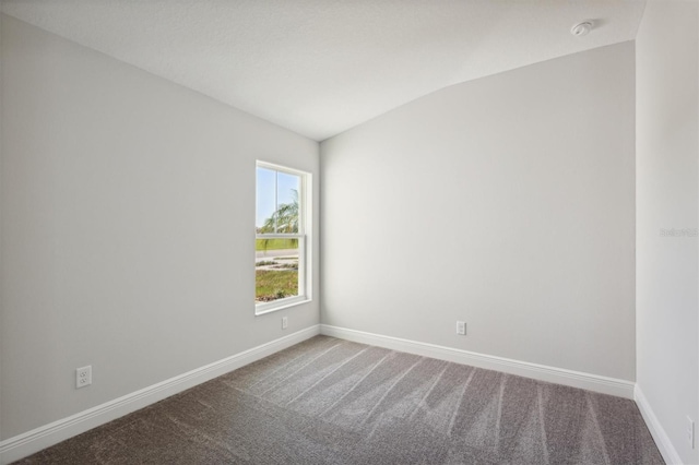 carpeted spare room with lofted ceiling and baseboards