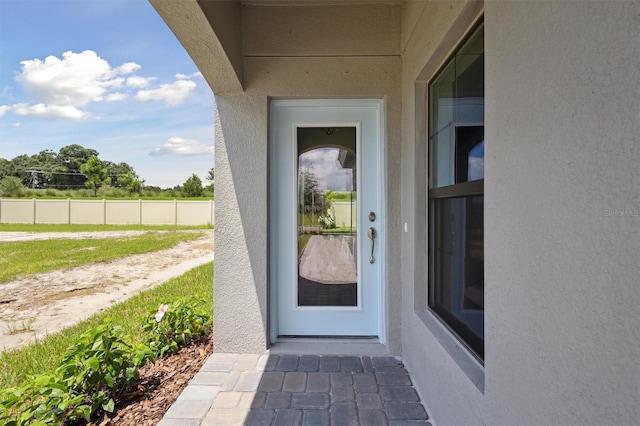 doorway to property featuring fence and stucco siding