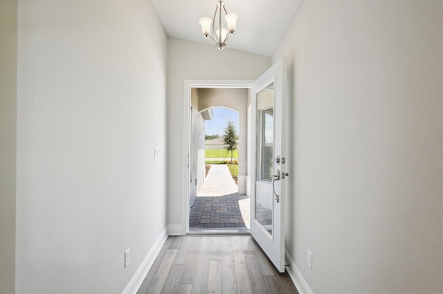 entryway with vaulted ceiling, an inviting chandelier, and hardwood / wood-style flooring