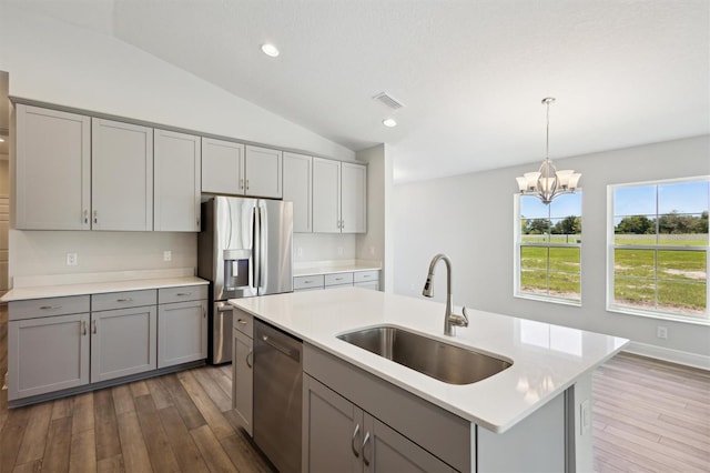 kitchen with appliances with stainless steel finishes, sink, a kitchen island with sink, and hardwood / wood-style flooring