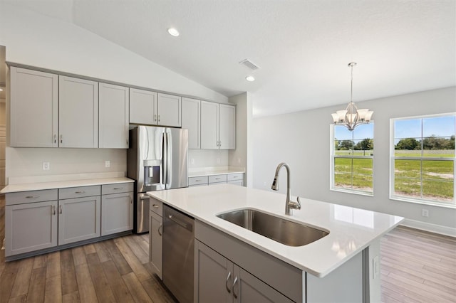 kitchen featuring appliances with stainless steel finishes, light countertops, a sink, and gray cabinetry