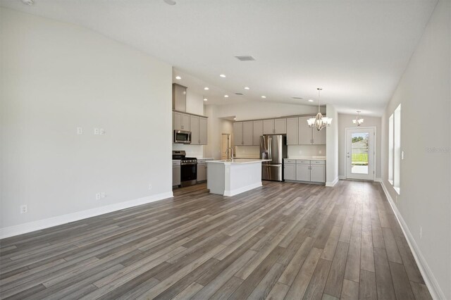 unfurnished living room featuring a notable chandelier, sink, hardwood / wood-style flooring, and vaulted ceiling