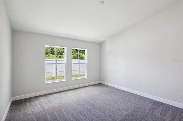 unfurnished room featuring carpet and baseboards