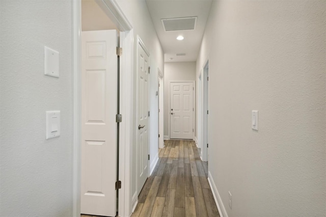 hall with wood finished floors, visible vents, and baseboards