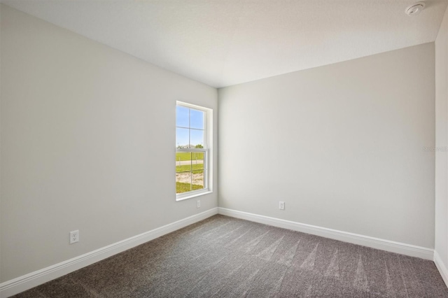 spare room featuring carpet and baseboards