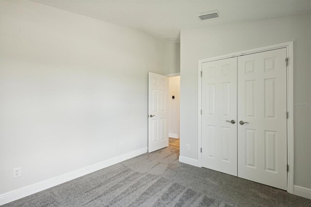 unfurnished bedroom featuring vaulted ceiling, light carpet, and a closet