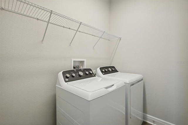 laundry area with laundry area, separate washer and dryer, and baseboards