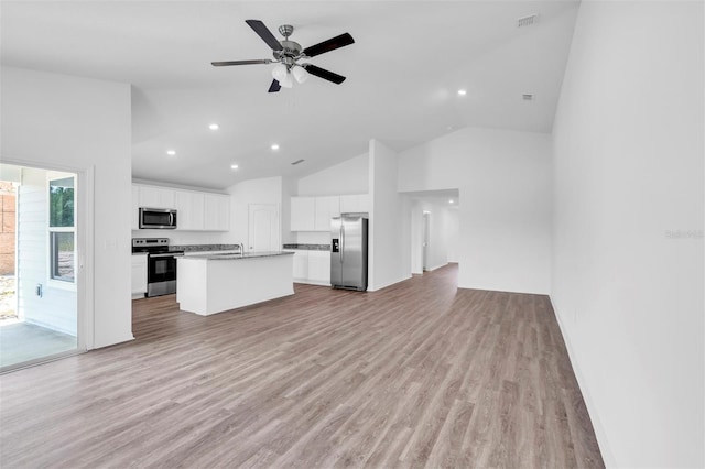 kitchen with white cabinets, stainless steel appliances, light hardwood / wood-style flooring, and a center island with sink