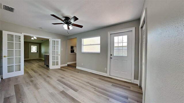 doorway with ceiling fan, visible vents, baseboards, french doors, and light wood-type flooring