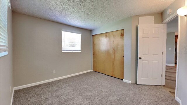 unfurnished bedroom featuring a textured ceiling, a closet, carpet, and baseboards