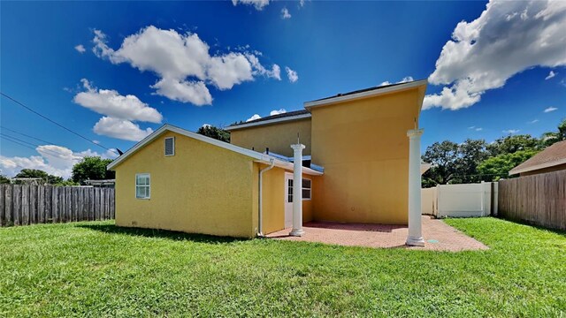 back of property with a fenced backyard, a lawn, a patio, and stucco siding