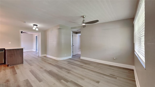 empty room with ceiling fan, light wood-type flooring, and baseboards