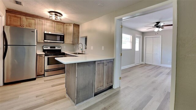 kitchen featuring light wood finished floors, visible vents, appliances with stainless steel finishes, light countertops, and a sink