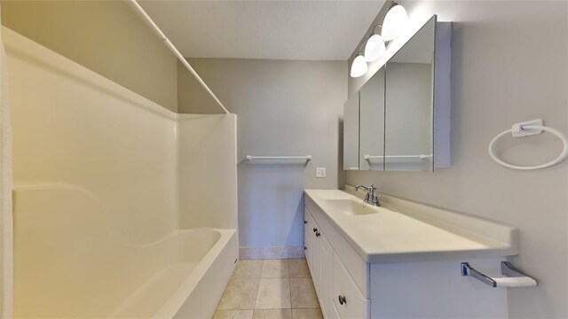 full bath with tub / shower combination, tile patterned flooring, vanity, and baseboards