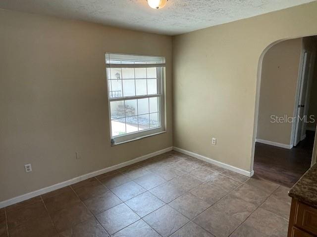 tiled spare room featuring a textured ceiling