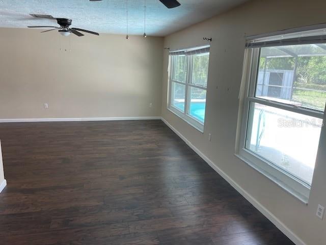 unfurnished room with dark hardwood / wood-style flooring, ceiling fan, and a textured ceiling