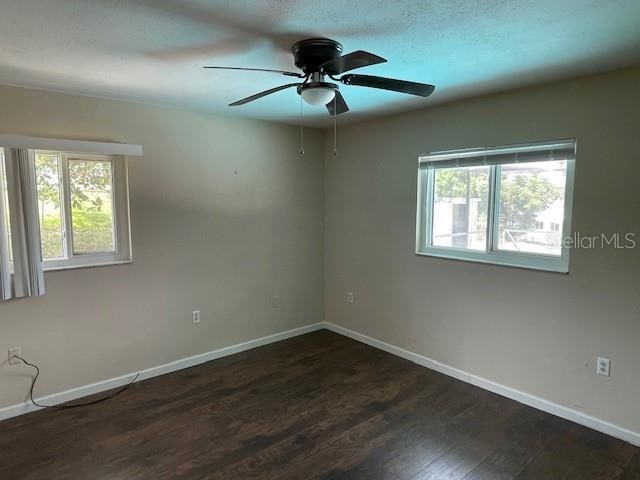 spare room featuring a textured ceiling, plenty of natural light, ceiling fan, and dark hardwood / wood-style floors