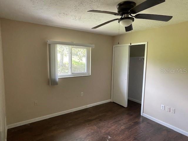 unfurnished bedroom with a textured ceiling, ceiling fan, dark hardwood / wood-style floors, and a closet