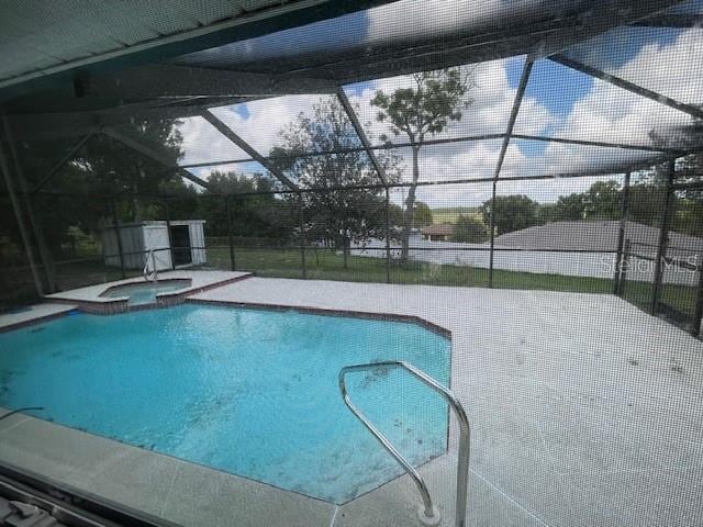 view of pool featuring glass enclosure, an in ground hot tub, and a patio