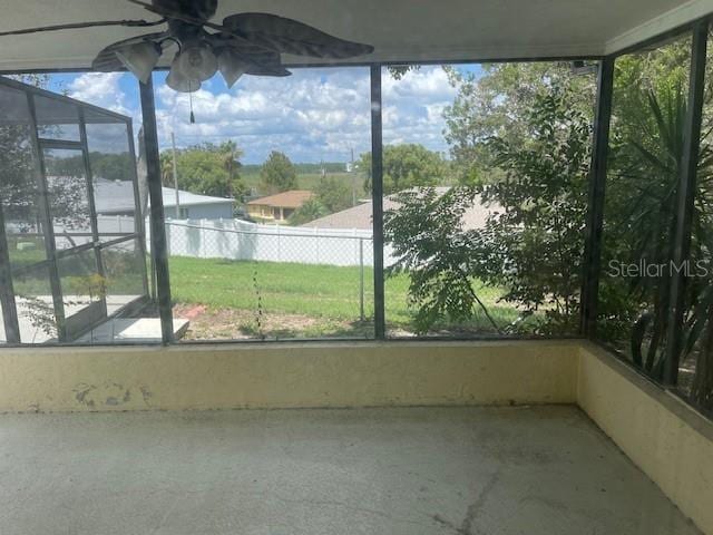 unfurnished sunroom with ceiling fan