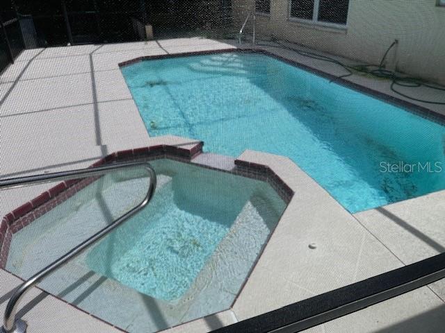 view of pool with a pool with connected hot tub