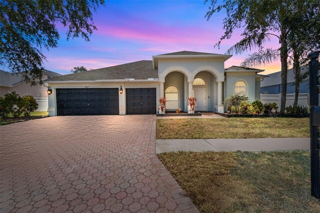 mediterranean / spanish-style house with a garage and a lawn