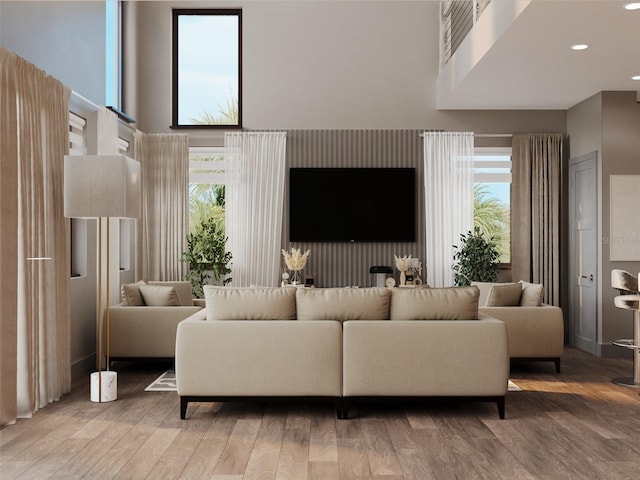 living area with a towering ceiling, wood finished floors, and recessed lighting