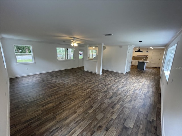 unfurnished living room with crown molding, dark wood-type flooring, and ceiling fan