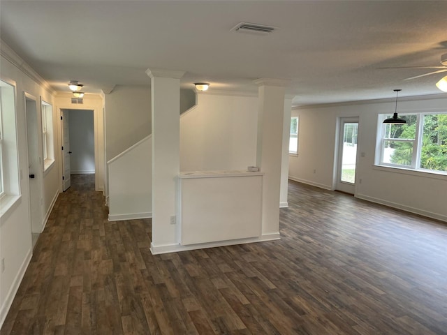 empty room with ornamental molding, dark wood-style flooring, visible vents, and baseboards