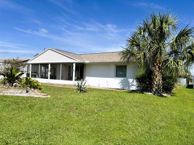 back of property with a sunroom and a lawn