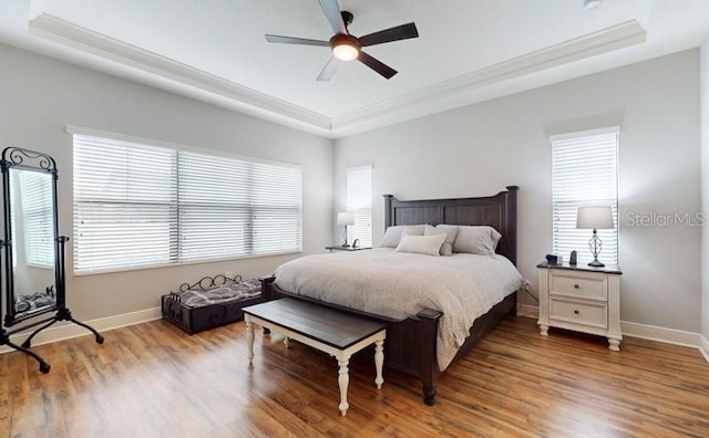 bedroom featuring ceiling fan, hardwood / wood-style floors, a tray ceiling, and ornamental molding