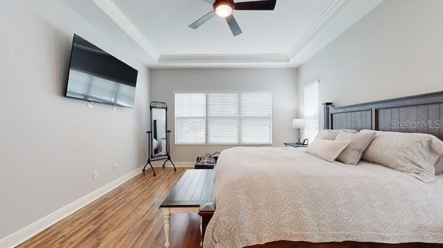 bedroom featuring ceiling fan, hardwood / wood-style floors, a tray ceiling, and ornamental molding