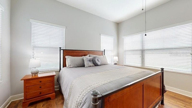 bedroom with vaulted ceiling, dark wood-type flooring, and multiple windows