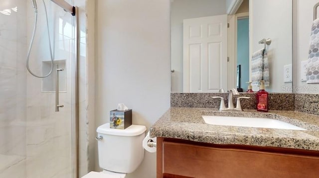 bathroom featuring toilet, a shower with shower door, and vanity