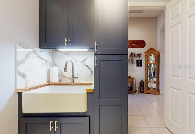 kitchen with light tile patterned floors, decorative backsplash, sink, and gray cabinets