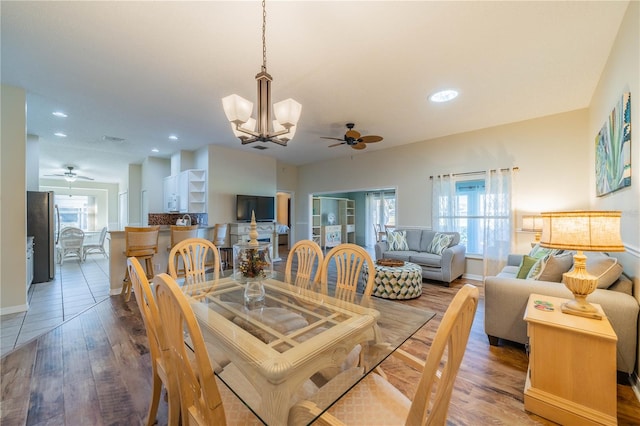 dining area featuring ceiling fan with notable chandelier and wood-type flooring