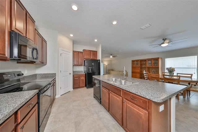 kitchen featuring sink, a textured ceiling, an island with sink, ceiling fan, and black appliances