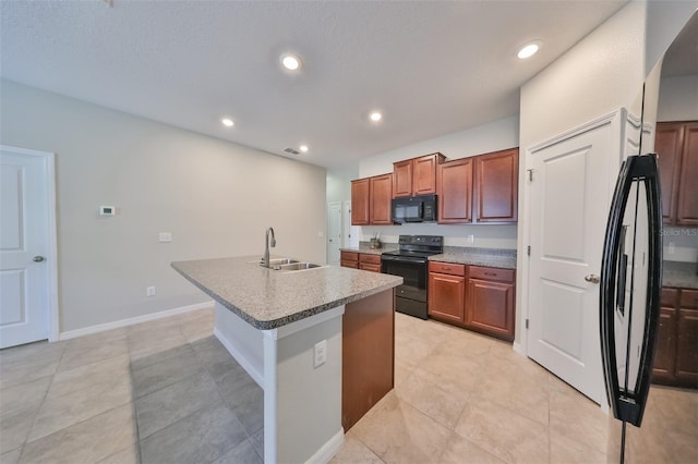 kitchen featuring light tile patterned flooring, sink, a breakfast bar area, a kitchen island with sink, and black appliances