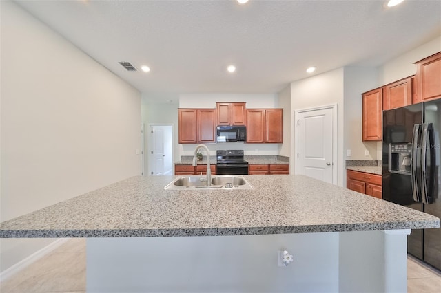 kitchen featuring sink, black appliances, a textured ceiling, and a center island with sink