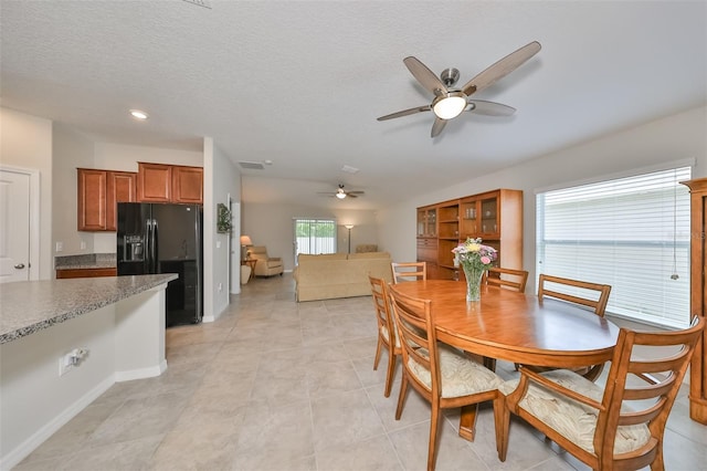 dining space with ceiling fan, light tile patterned floors, and a textured ceiling