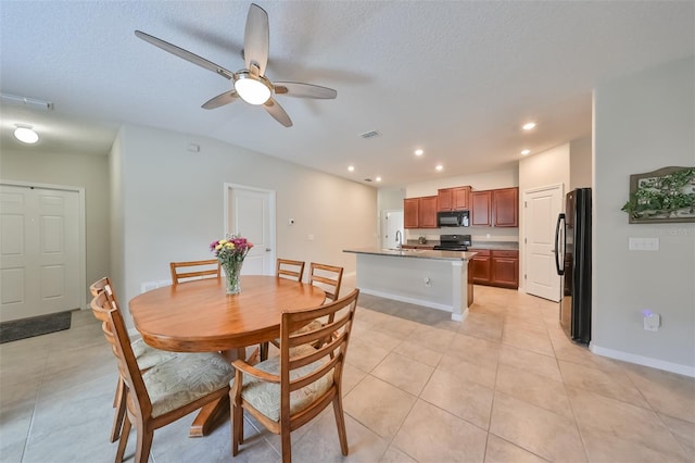 tiled dining room featuring ceiling fan, sink, and a textured ceiling