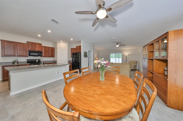 dining area with sink, a textured ceiling, and light tile patterned floors