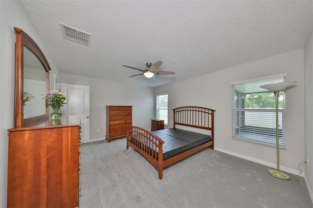 carpeted bedroom featuring ceiling fan and a textured ceiling