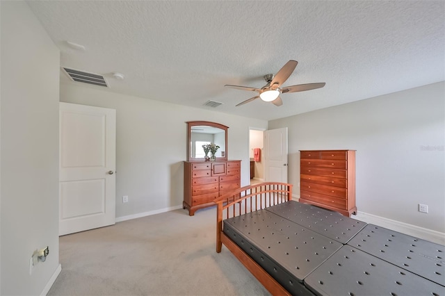 bedroom with ceiling fan, light colored carpet, and a textured ceiling