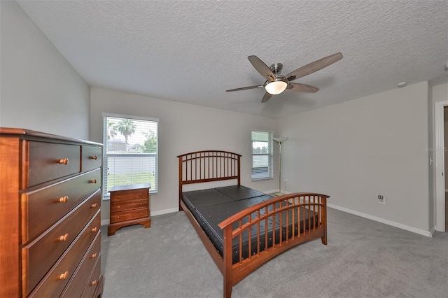 carpeted bedroom featuring ceiling fan, multiple windows, and a textured ceiling