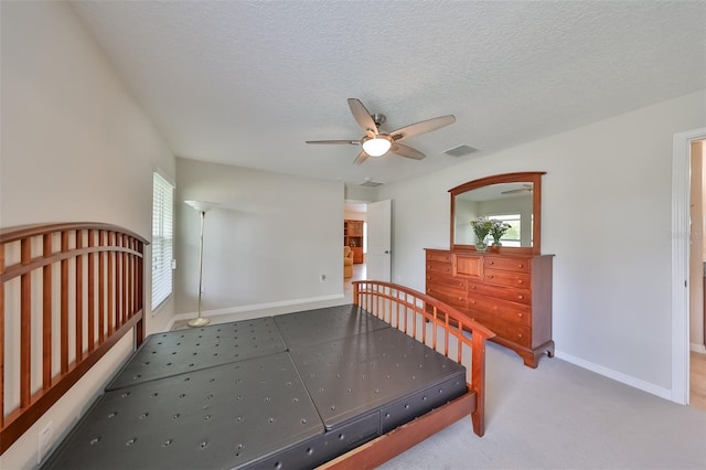 carpeted bedroom featuring ceiling fan and a textured ceiling