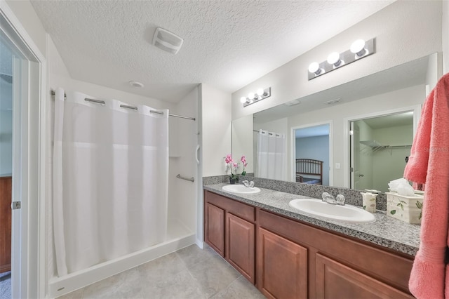 bathroom with walk in shower, tile patterned floors, vanity, and a textured ceiling