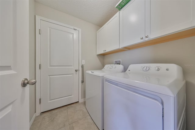 washroom with light tile patterned flooring, cabinets, washer and dryer, and a textured ceiling