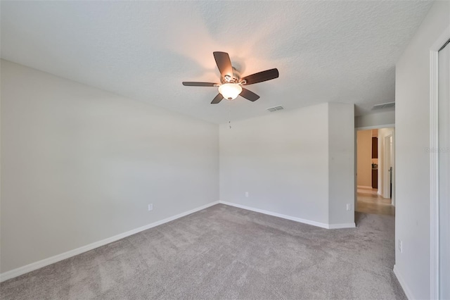 empty room with ceiling fan, light carpet, and a textured ceiling