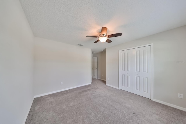 unfurnished bedroom featuring ceiling fan, carpet floors, a closet, and a textured ceiling